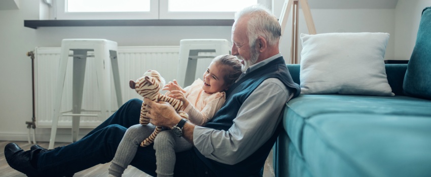 A grandfather playing with his granddaughter.