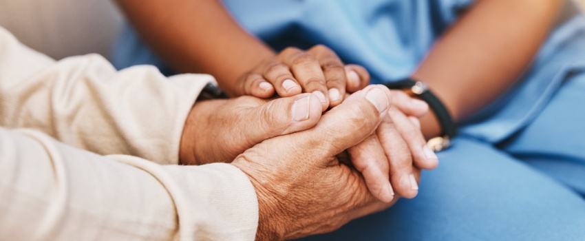 An elderly person holding hands with a nurse.