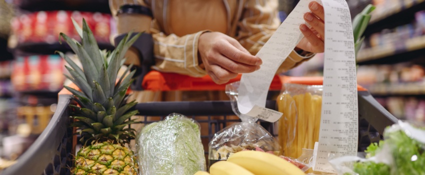 A woman looking at a receipt in a supermarket.