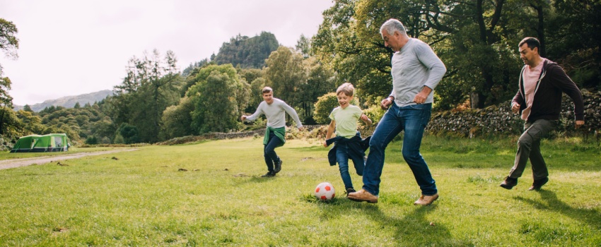 Multi-generational family playing football in a park.